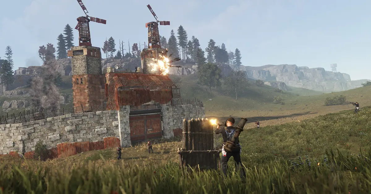 A player stands outside a fortified metal base in Rust, holding a crafted assault rifle at dawn.